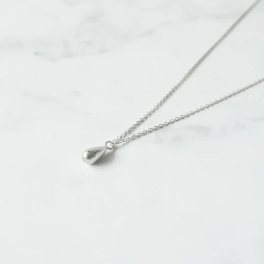 以柔和水滴輪廓為靈感設計的極簡風格項鍊，線條流暢、比例俐落，呈現出低調卻耐看的優雅氣質。