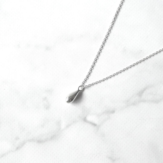 以柔和水滴輪廓為靈感設計的極簡風格項鍊，線條流暢、比例俐落，呈現出低調卻耐看的優雅氣質。